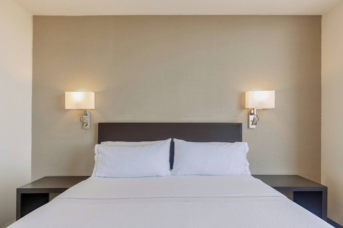 A neatly made bed with white linens and two bedside lamps on either side.