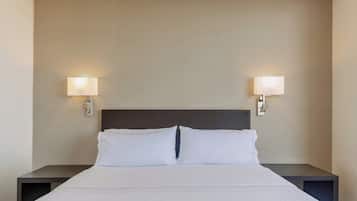 A neatly made bed with white linens and two bedside lamps on either side.