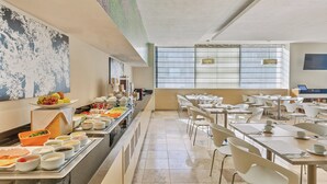 Montaje de bufé con diversas opciones de comida y una zona de estar con mesas y sillas.