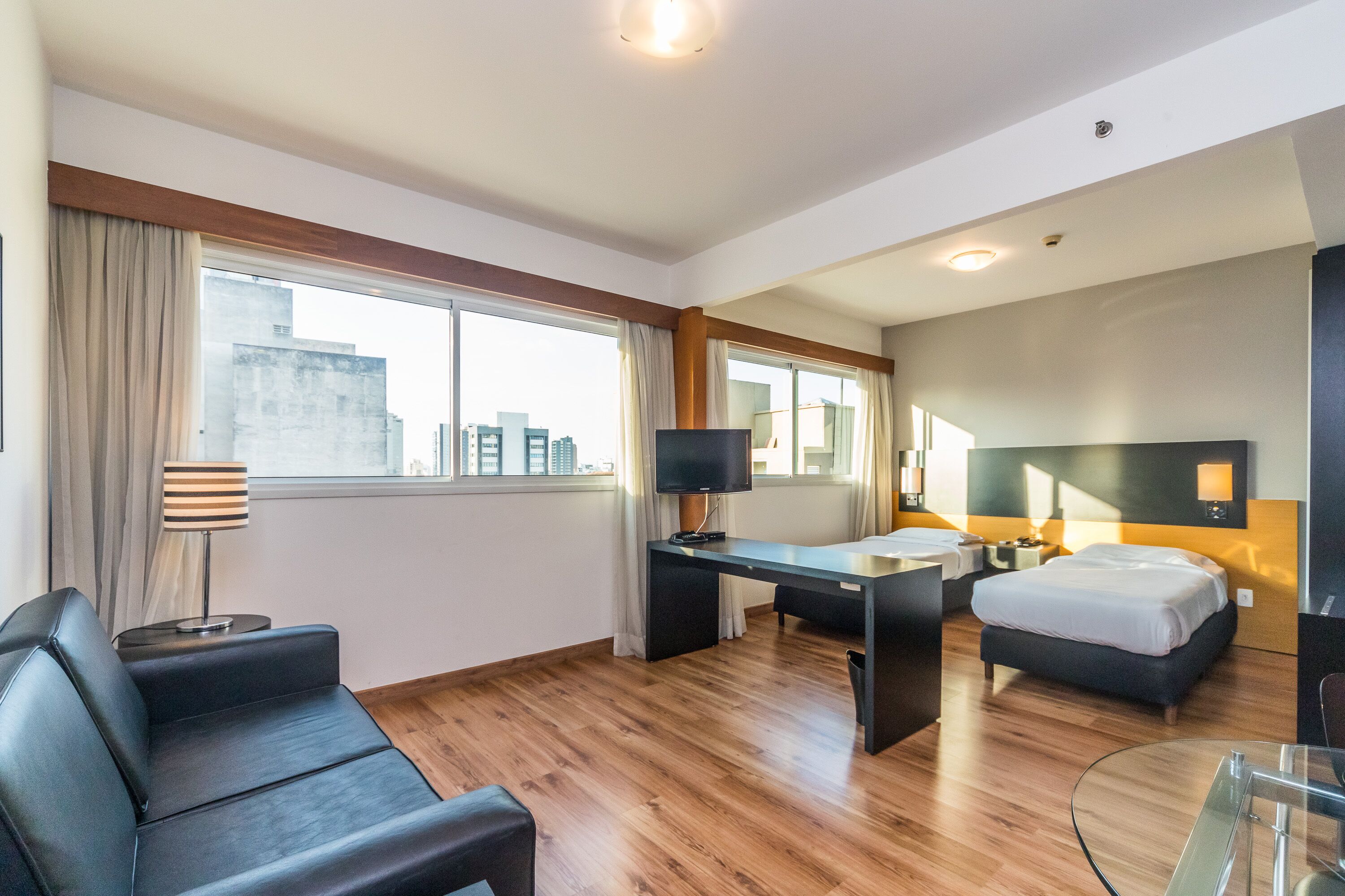 Una habitación de hotel moderna con una cama grande, un escritorio, un sofá y una mesa de vidrio.