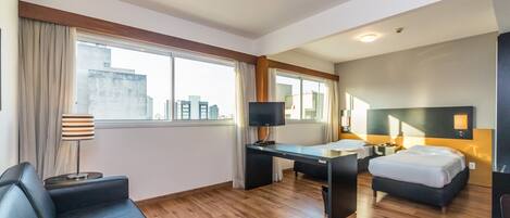 Una habitación de hotel moderna con una cama grande, un escritorio, un sofá y una mesa de vidrio.