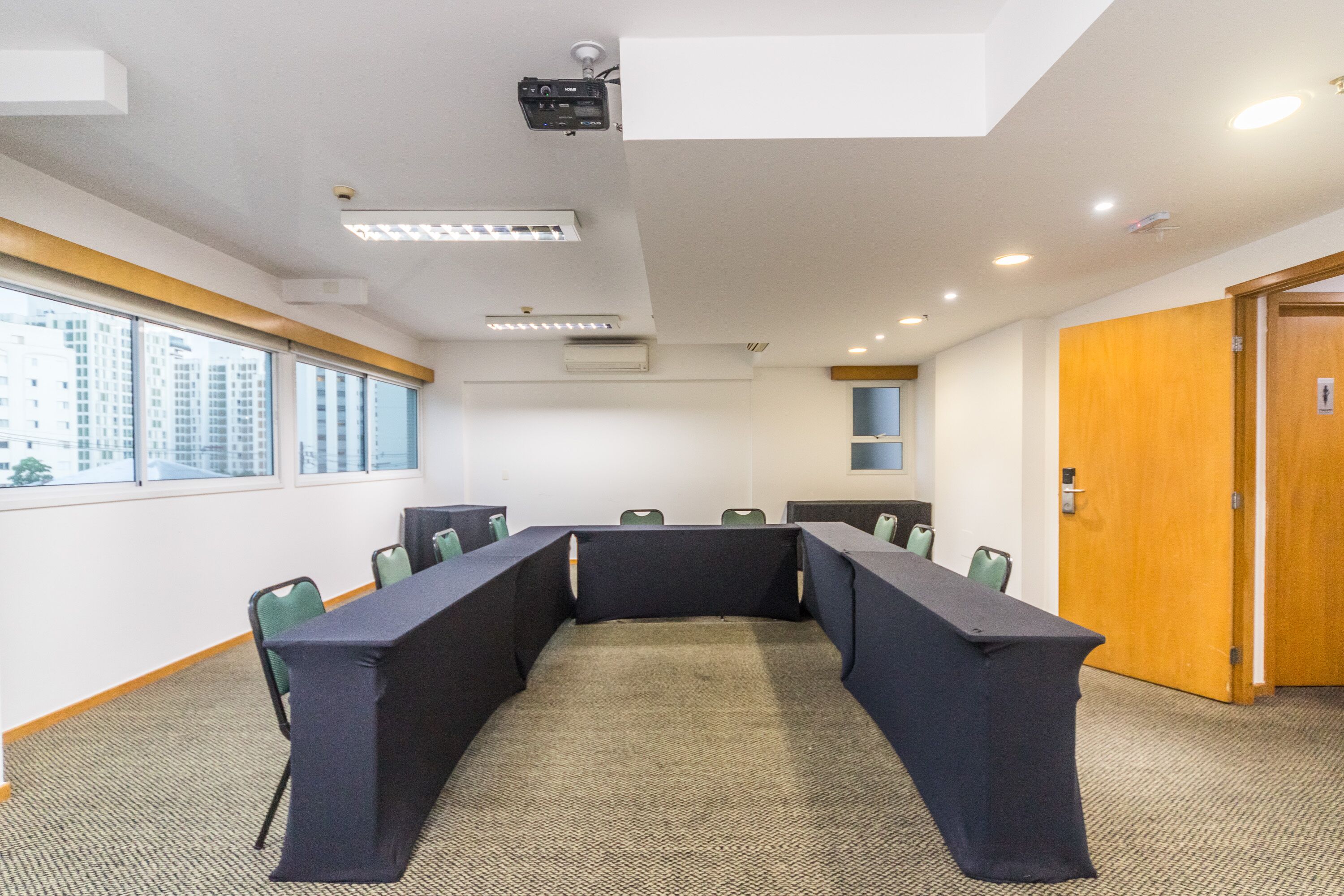 Een vergaderzaal met een lange tafel, stoelen en een projector.