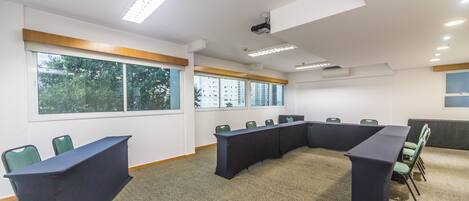 A conference room with a long table, multiple chairs, and large windows.