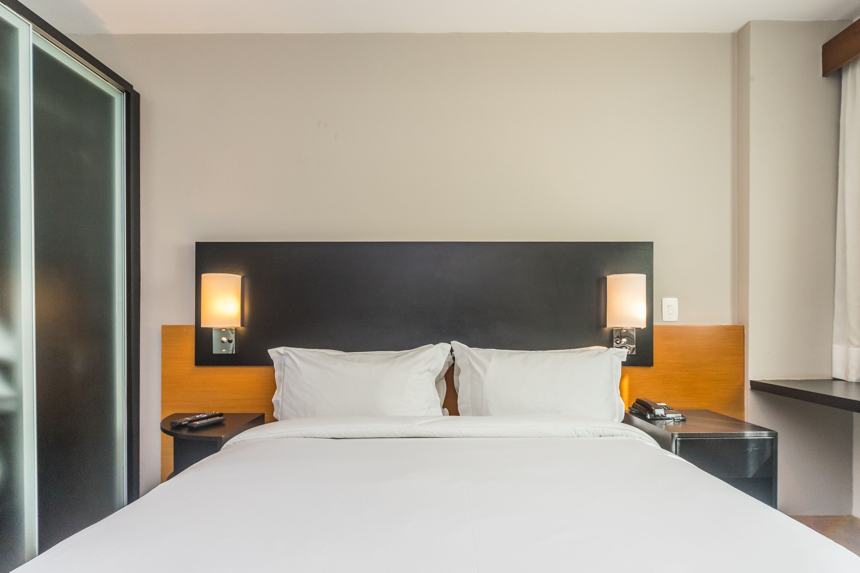 Habitació d'hotel amb un llit gran, dues taules de nit i làmpades penjades a la paret.