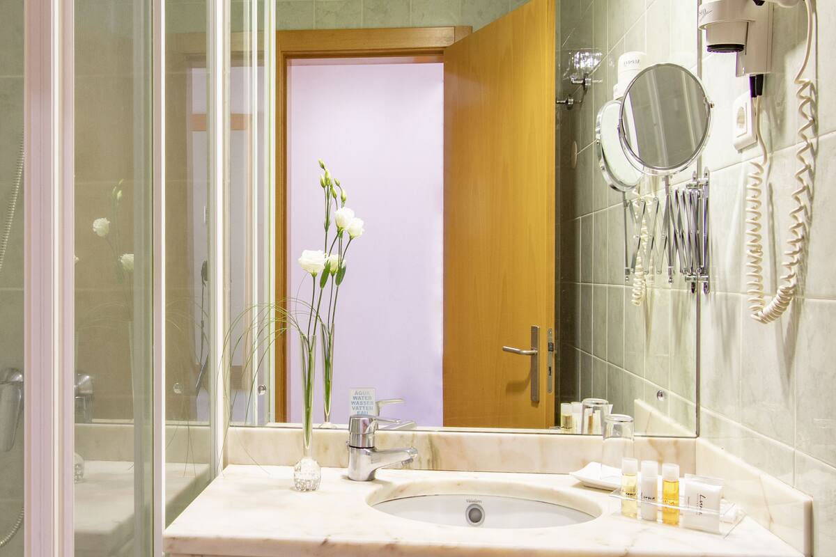 A bathroom with a sink, mirror, and shower.