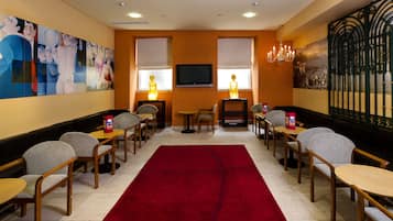 A hotel room with a red carpet, wooden furniture, a flat-screen TV, and artwork on the walls.