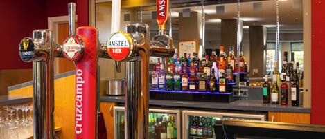 A bar area with multiple beer taps including brands like Amstel and Cruzcampo, and a well-stocked liquor shelf.