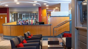 A modern lobby with a reception desk, seating area, and a staircase.