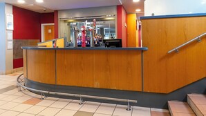 A reception area with a wooden counter, a staircase, and a view of the lobby.
