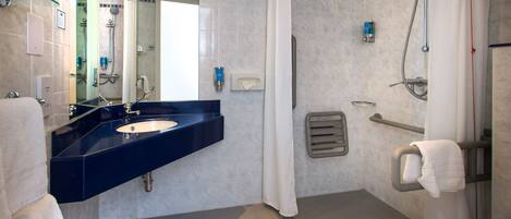 A modern bathroom with a dark blue sink, a white toilet, and a shower area.