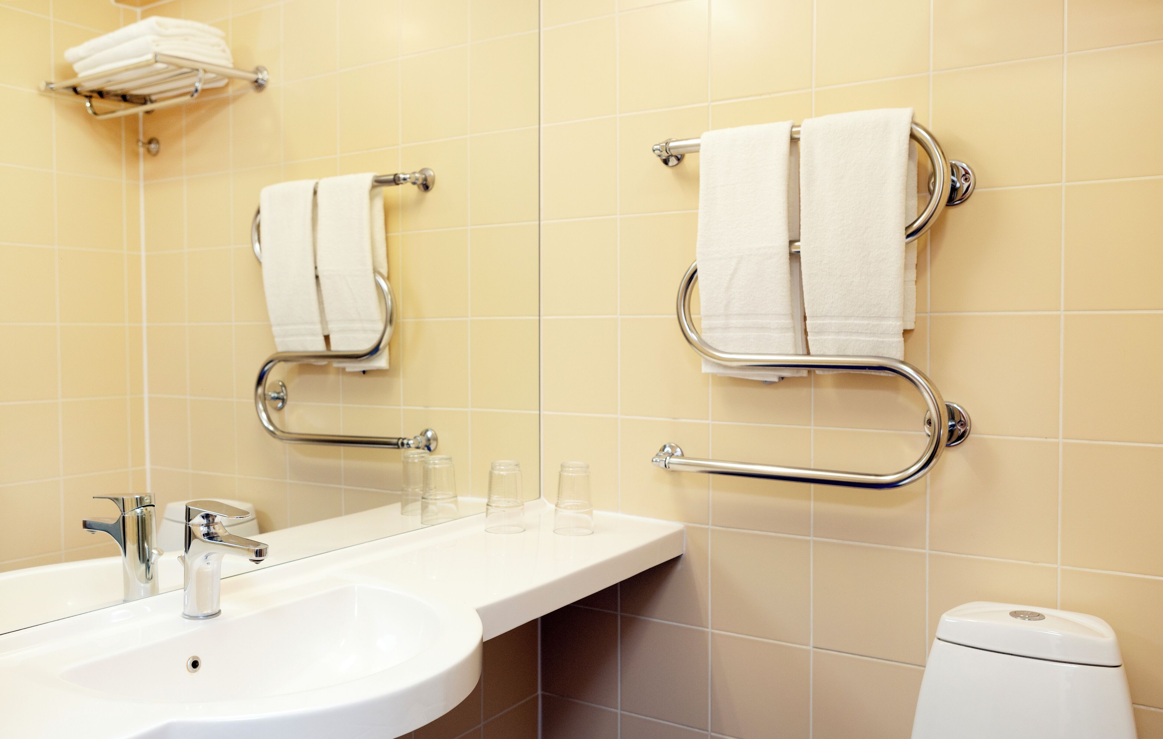 Un baño con lavamanos, dos toalleros, un inodoro y un espejo.
