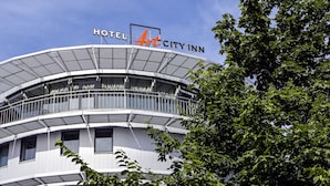 Un hôtel moderne à la façade incurvée, doté de balcons et d’une enseigne bien visible indiquant « HÔTEL Art City Inn ».