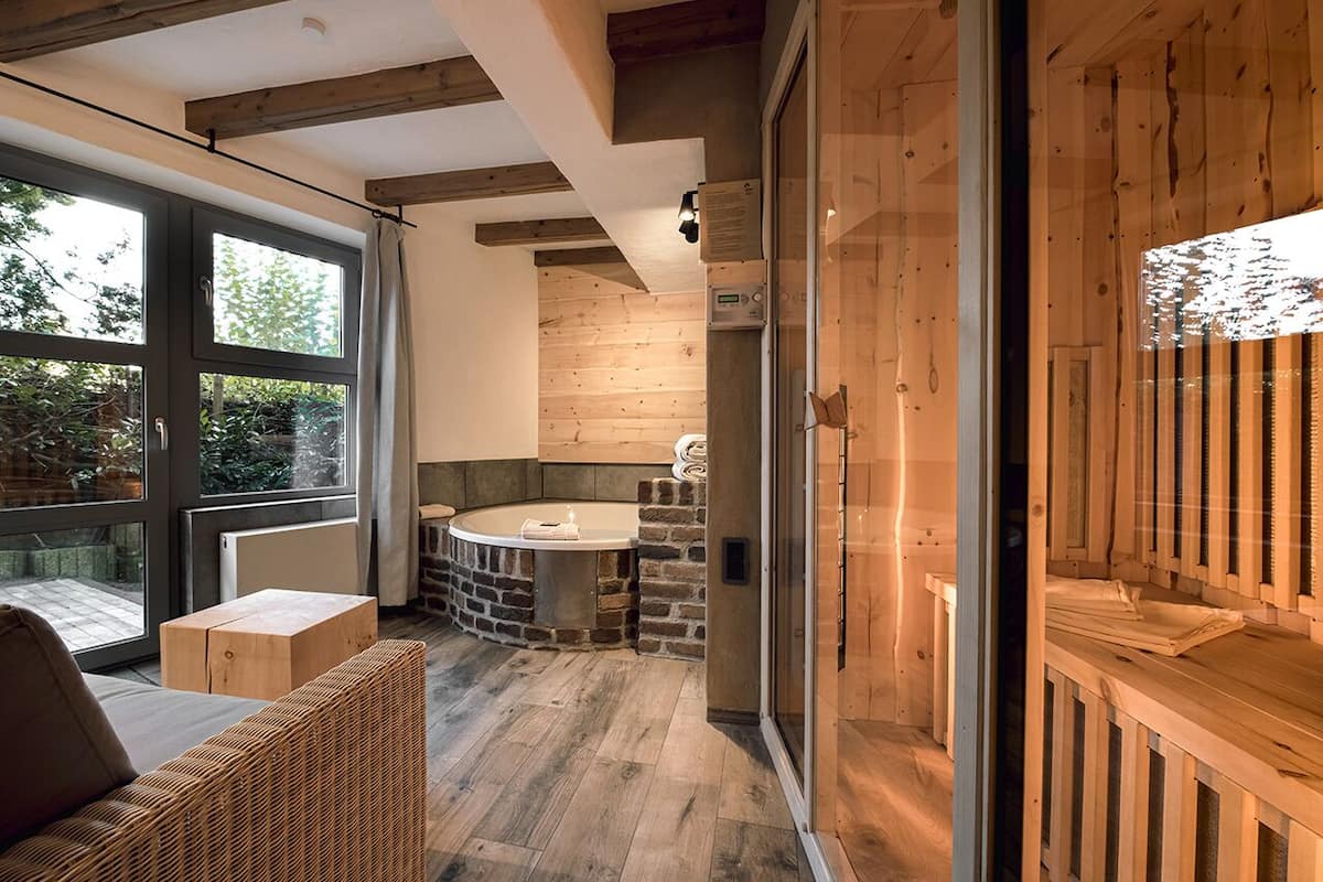 A modern interior with a stone fireplace, a wooden bench, and a glass door leading to an outdoor area.