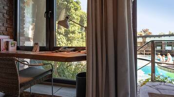 A room with a desk, chair, and a view of an outdoor swimming pool.