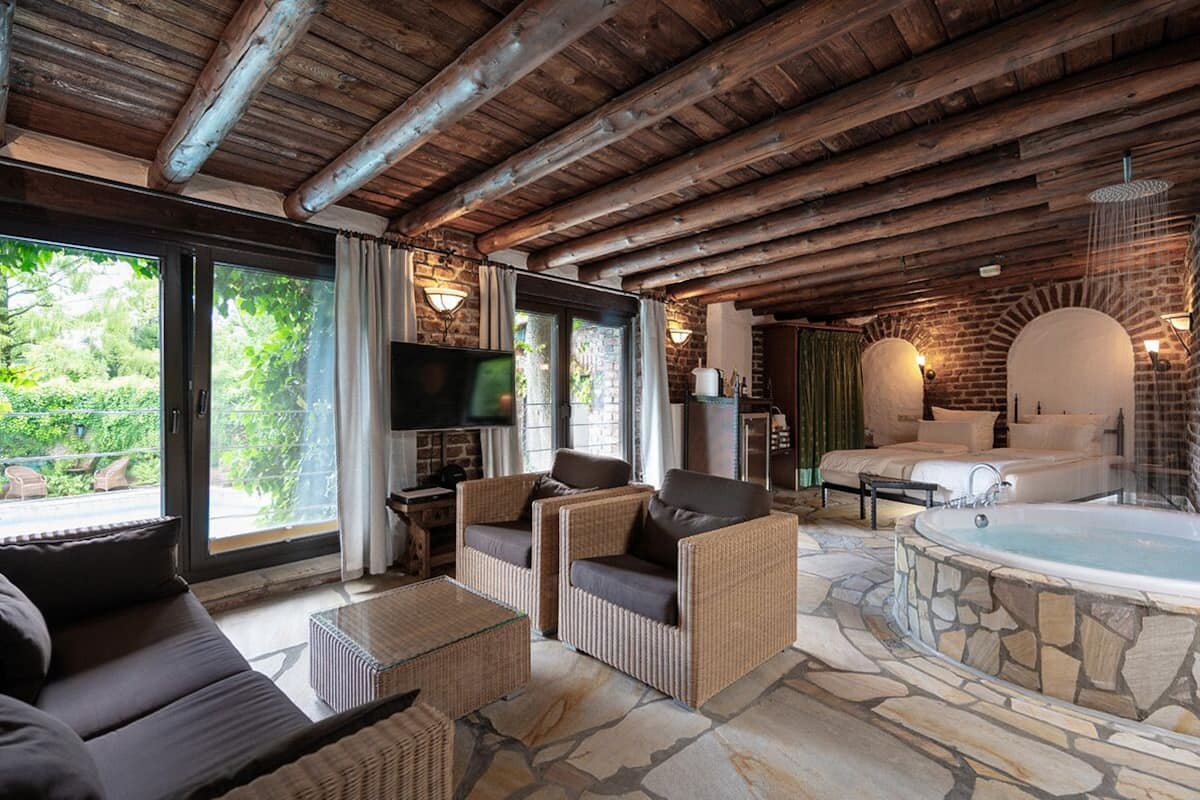 A cozy room with wicker furniture, a stone floor, a stone bathtub, and a TV.