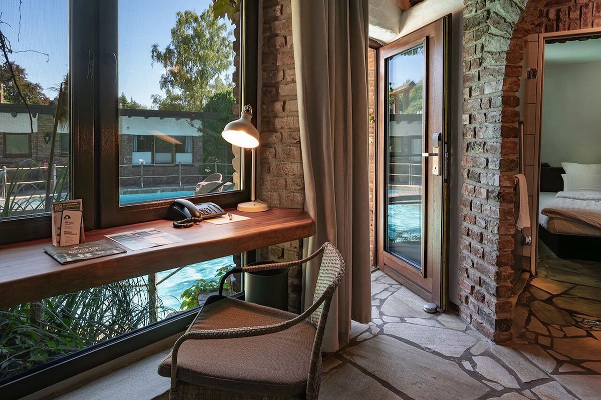 A room with a desk, chair, and a view of the ocean through large windows.