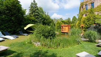Relax in a serene garden setting surrounded by lush greenery and a charming wooden structure.