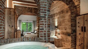 A spa room with a hot tub, wooden walls, and a view of the outdoors.