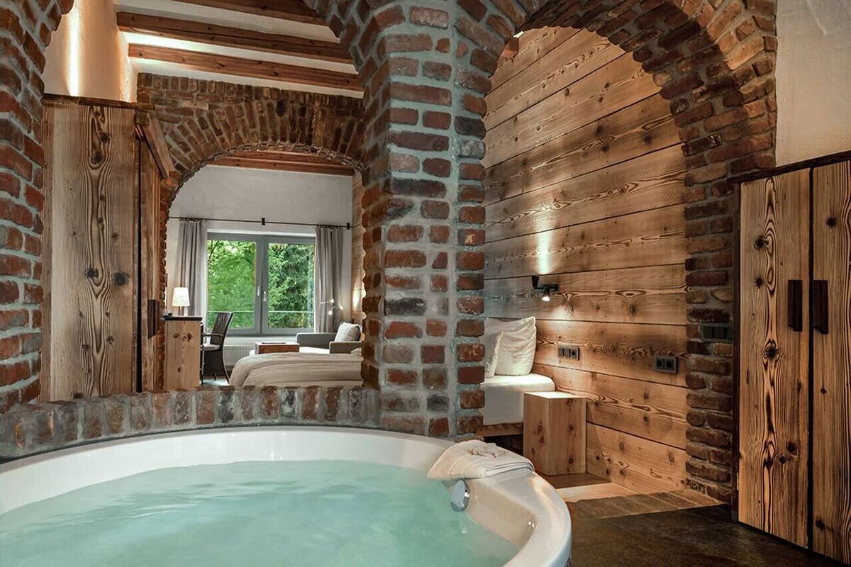 A spa room with a hot tub, wooden walls, and a view of the outdoors.