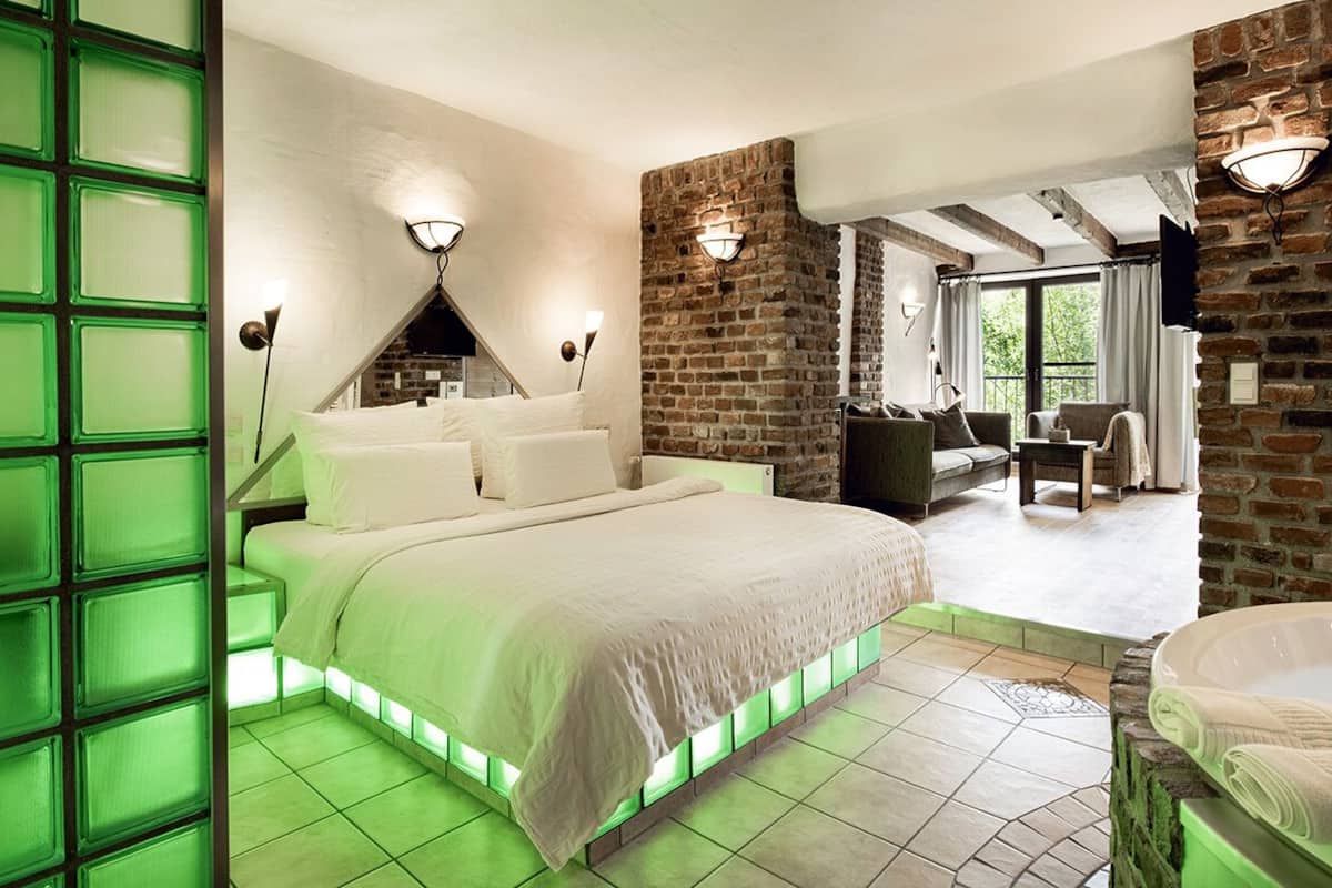 A bedroom with a large bed, a stone wall, and a view of the outdoors.