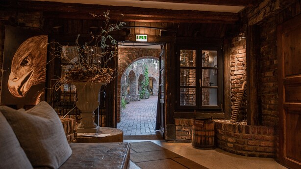 A cozy lobby with a large bird sculpture, a fireplace, and a view of a brick pathway leading outside.