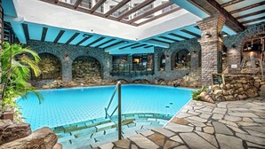 An indoor swimming pool with stone walls and a wooden ceiling.