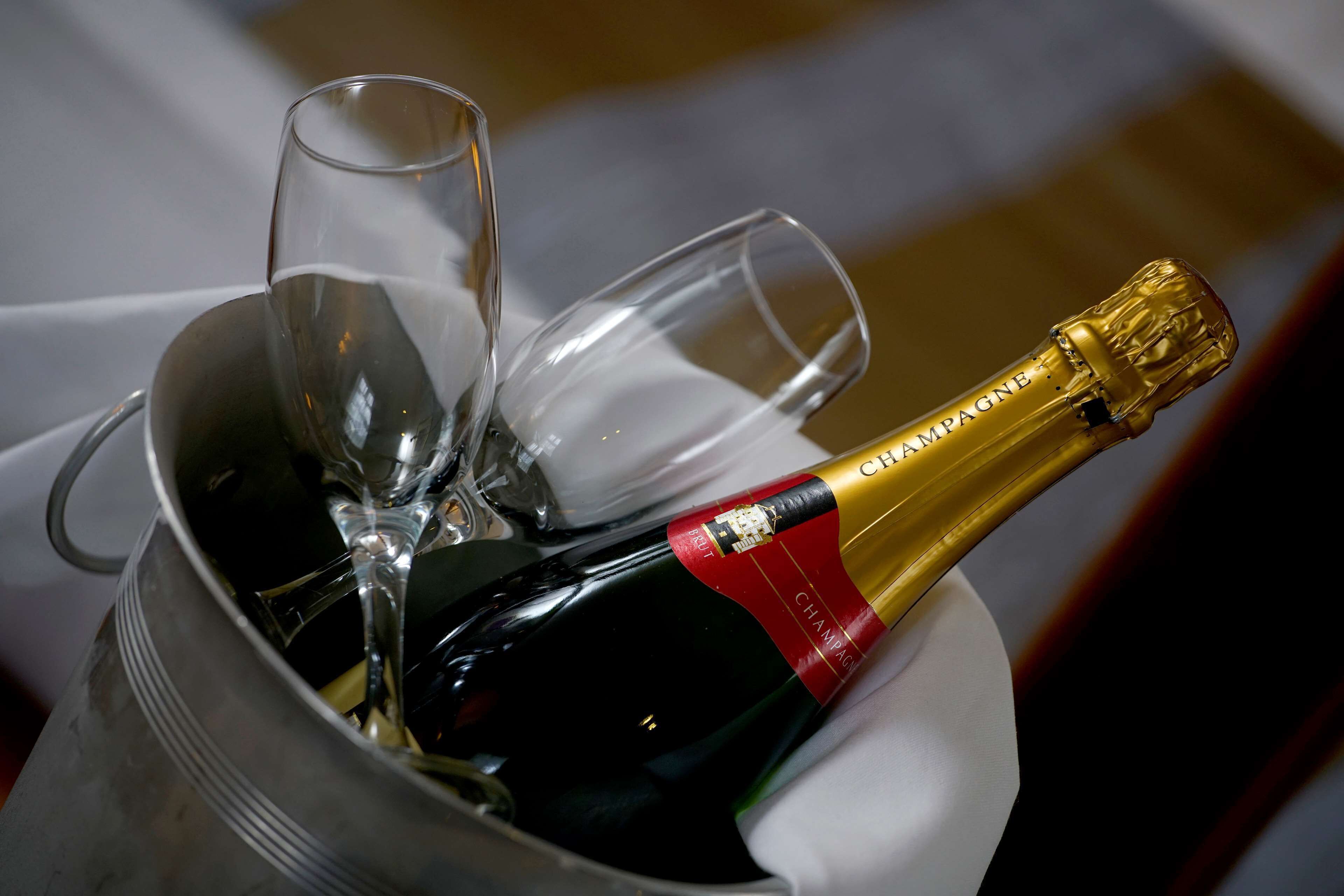 A bottle of champagne in a metal bucket with two glasses.