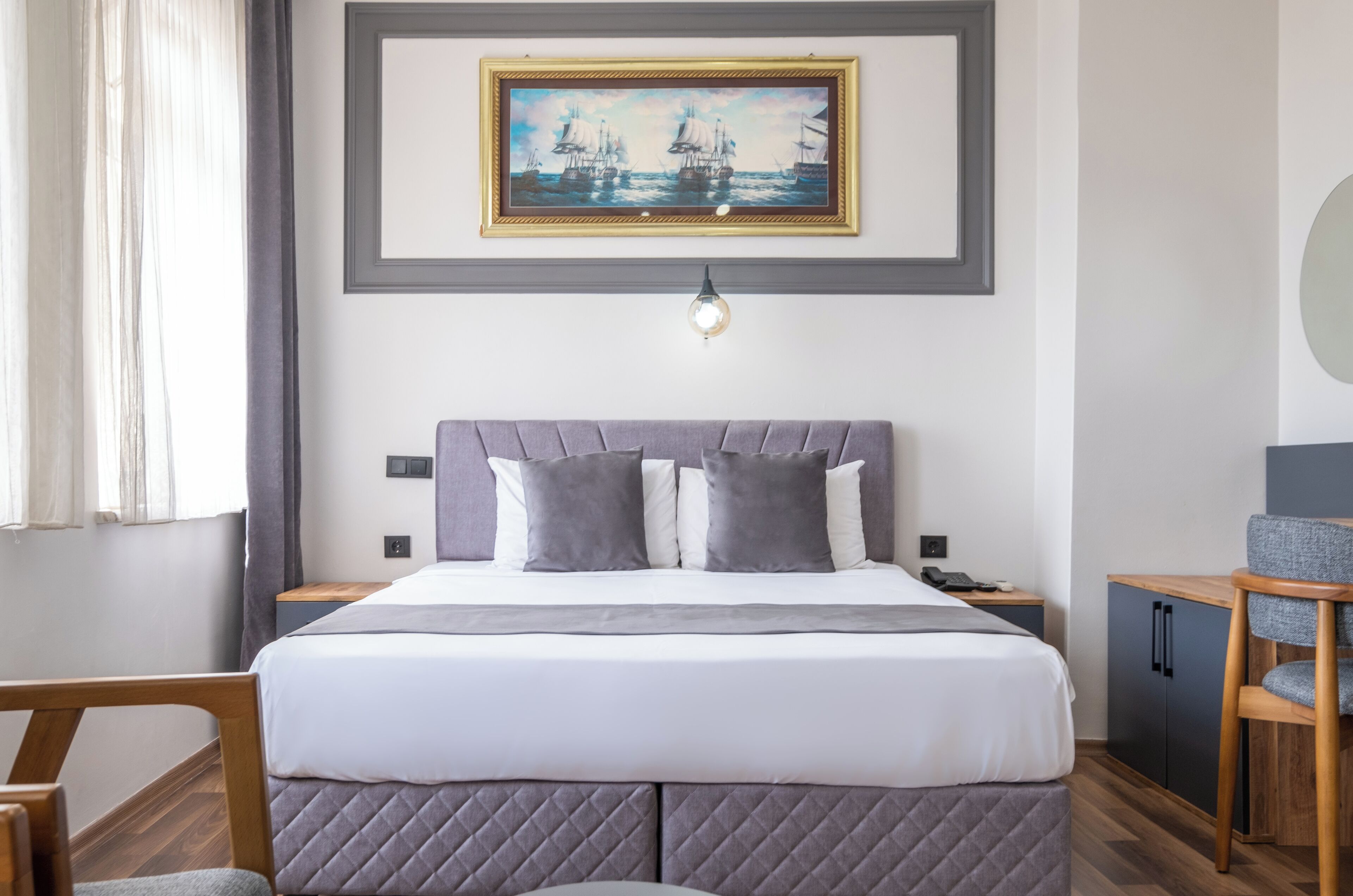 A neatly arranged bedroom with a bed, bedside tables, a desk, and a chair.