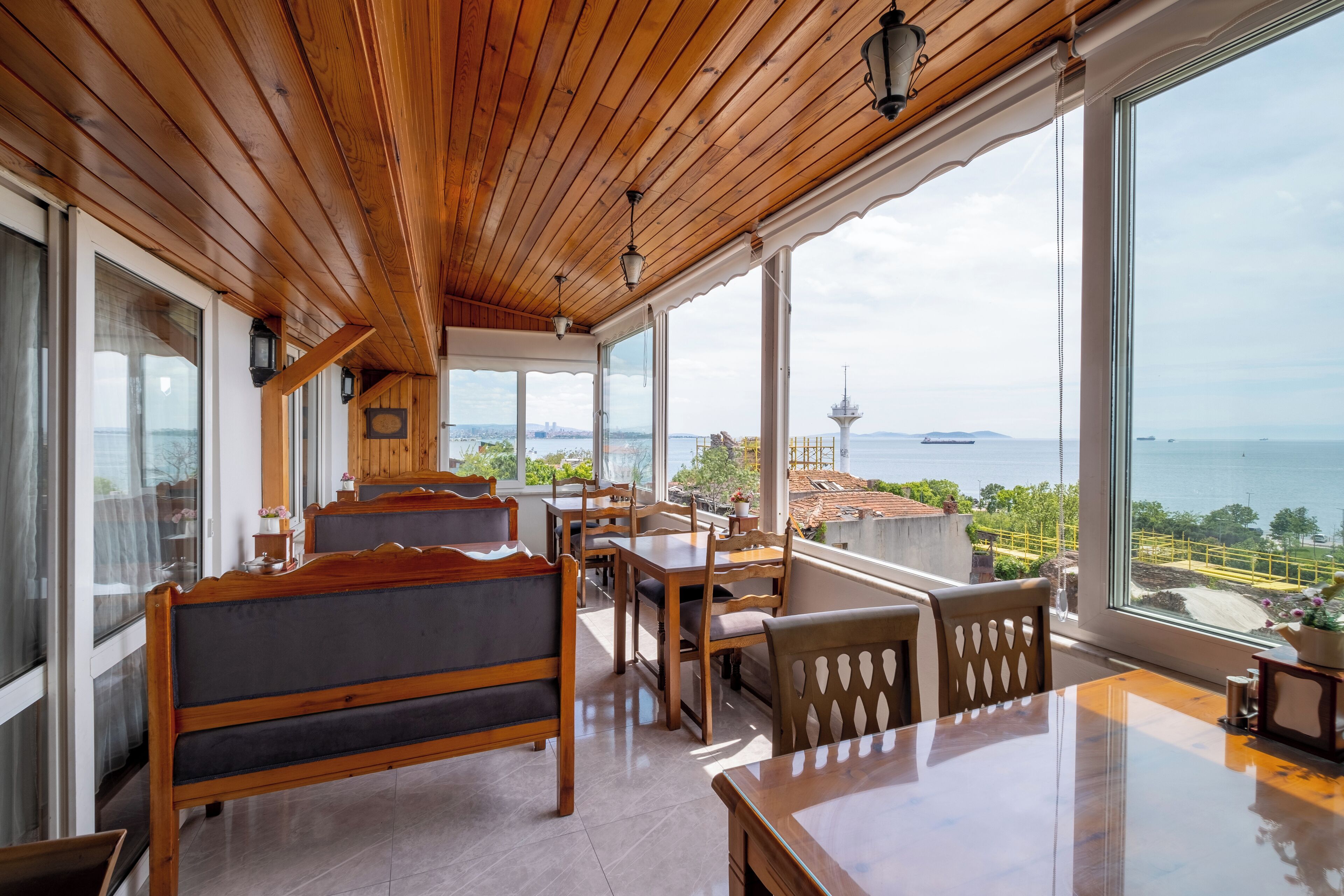 A wooden-paneled room with a view of the sea and a tower.