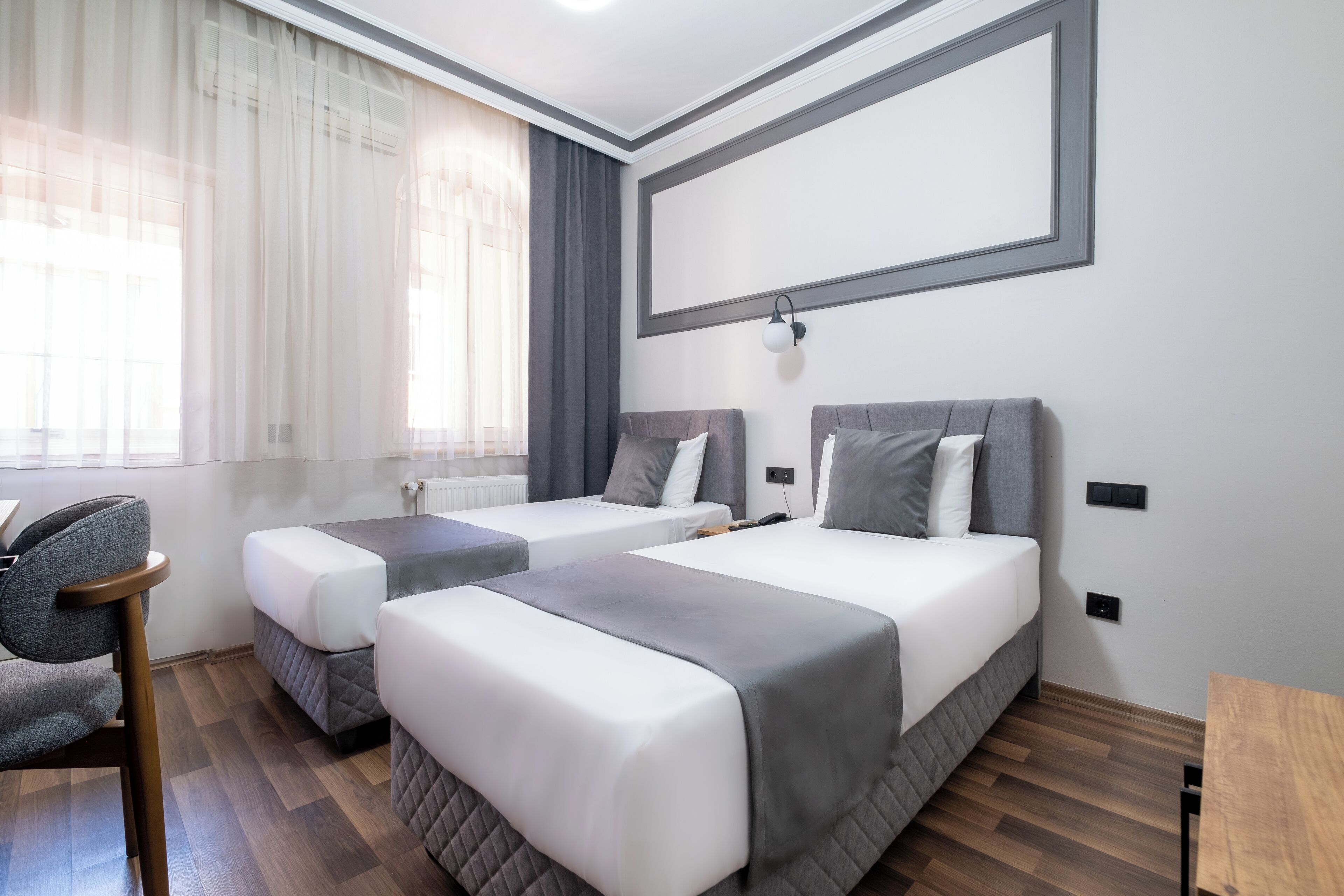 A hotel room with two beds, a desk, and a chair.
