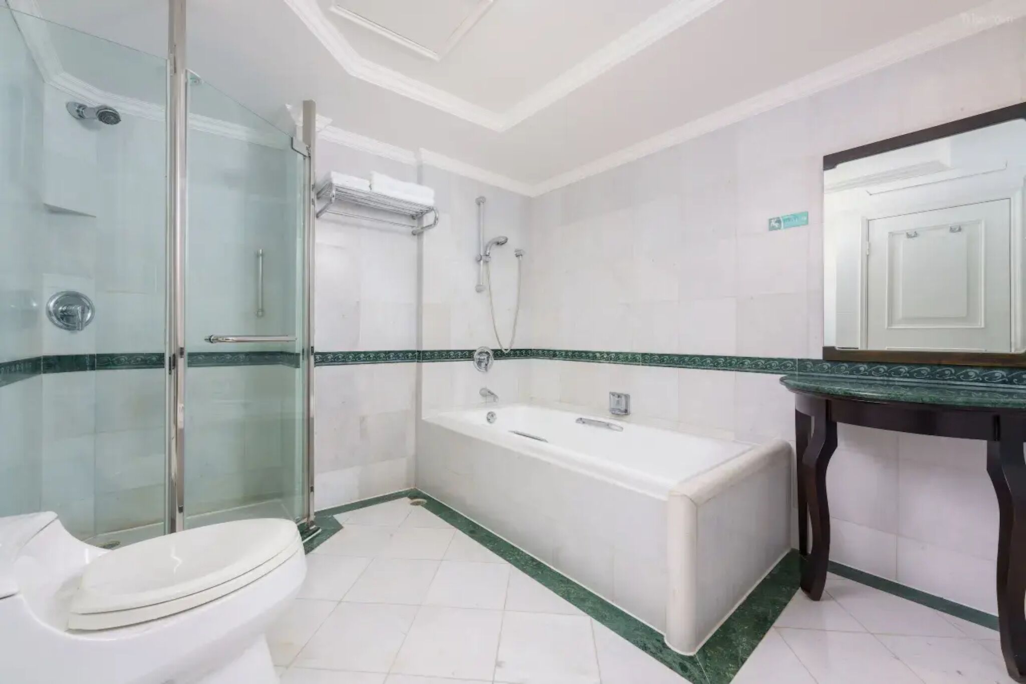 A bathroom with a glass shower enclosure, a bathtub, a toilet, and a vanity with a mirror.