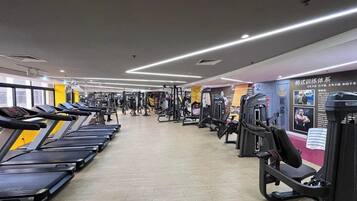 Une salle de sport équipée de tapis de course, d’appareils de musculation et d’un mur recouvert de miroirs.