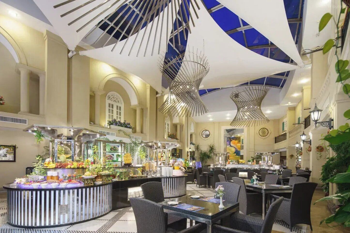 A hotel dining area with a buffet, round tables, and chairs.