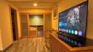 A hotel room with a wooden cabinet, a flat-screen TV displaying a show, and a microwave. - Hotel Colonial Ciudad Juarez (Ciudad Juárez)