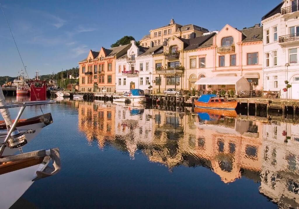 A waterfront property with a dock, boats, and buildings reflecting on the water.