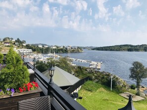 A riverside view with boats docked, a bridge with railings, and greenery. - Farsund Fjordhotell (Farsund)