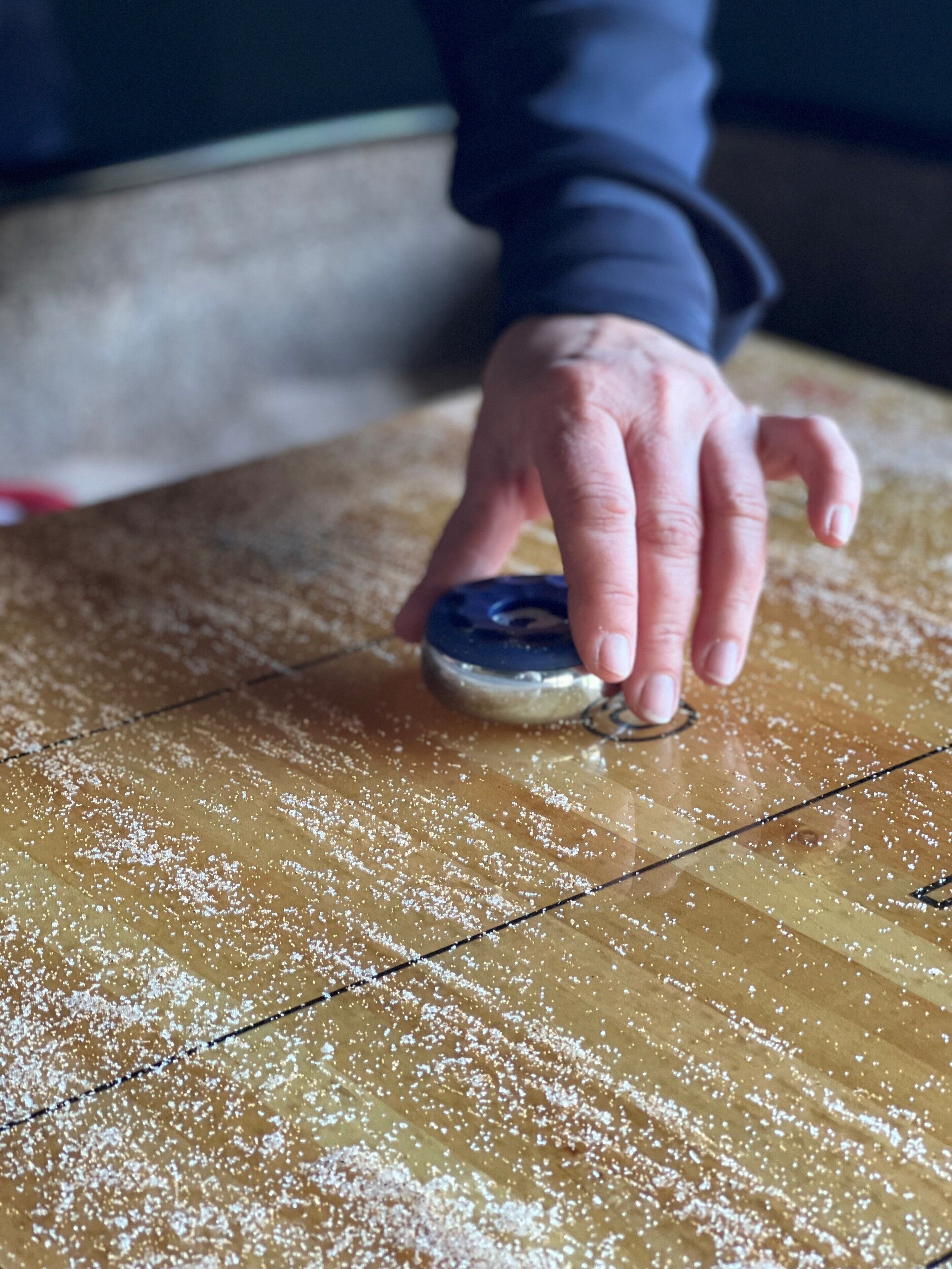 A hand using a measuring device on a wooden surface with white powder.
