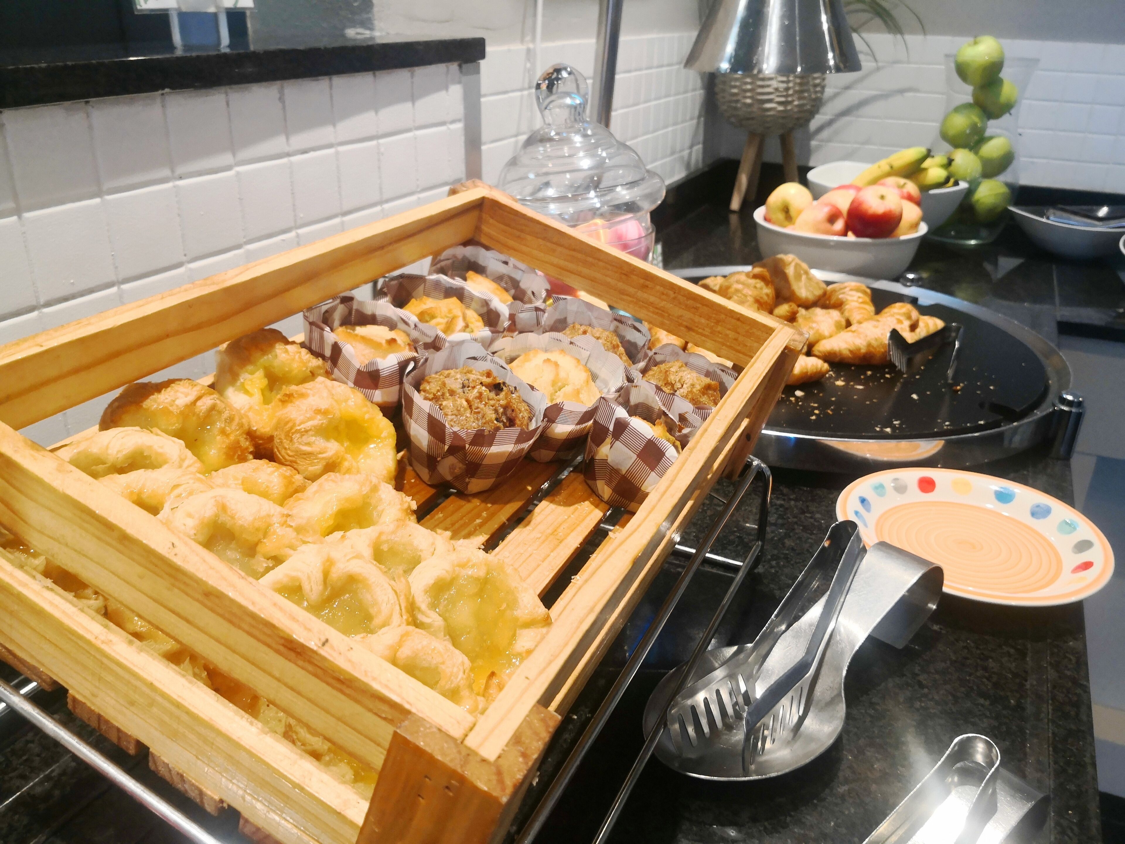 A buffet with various baked goods and fruits.