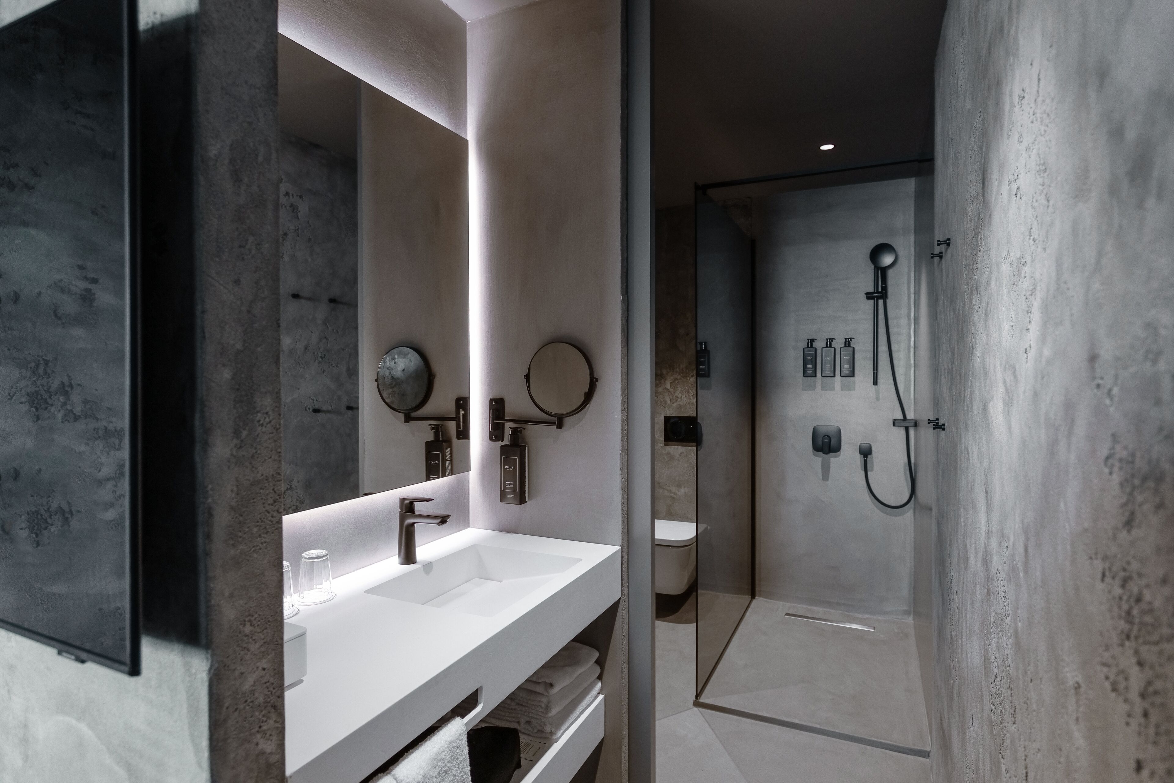 A modern bathroom with a white vanity, a large mirror, and a glass-enclosed shower area.