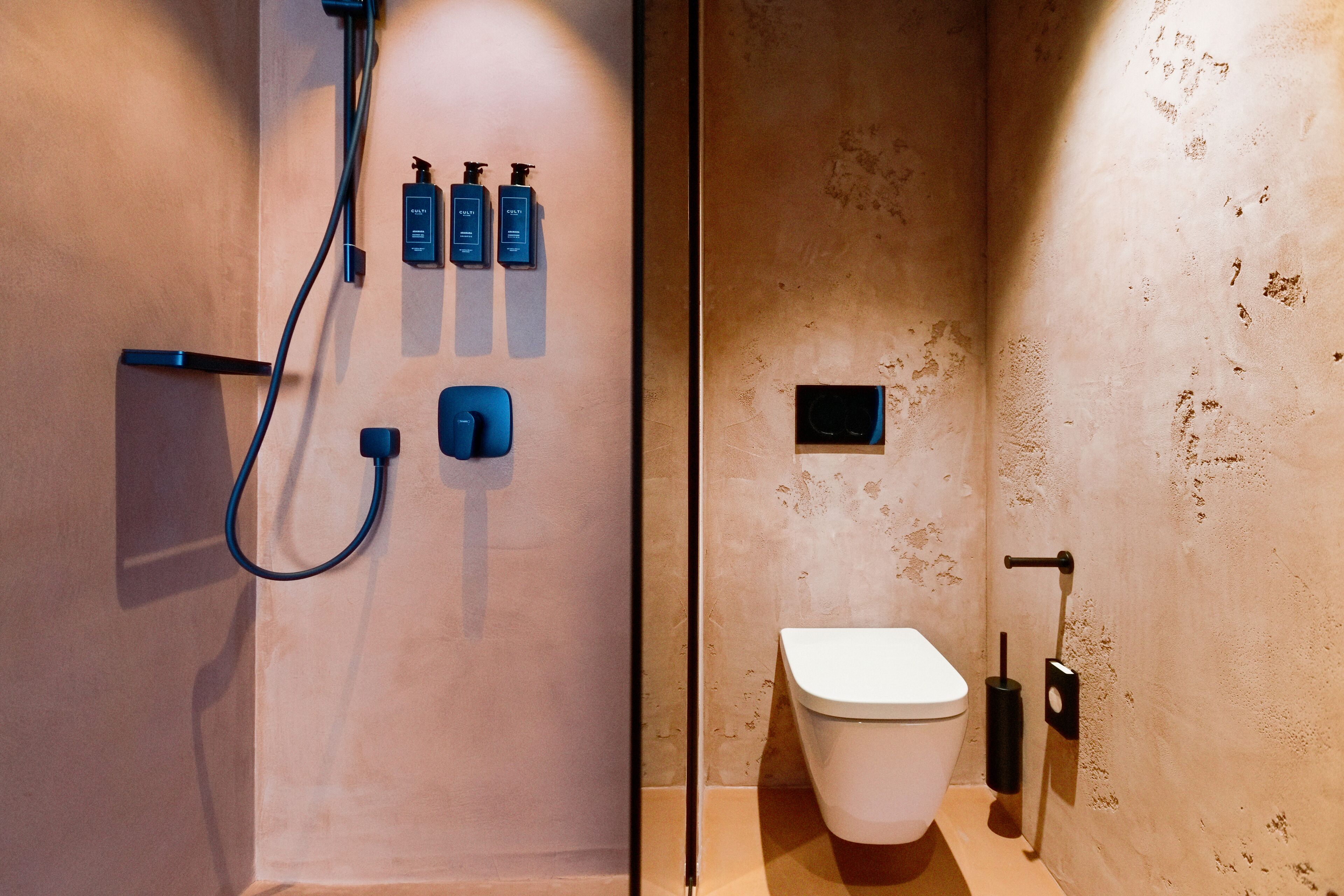 A modern bathroom with a shower, toilet, and hand soap dispensers.