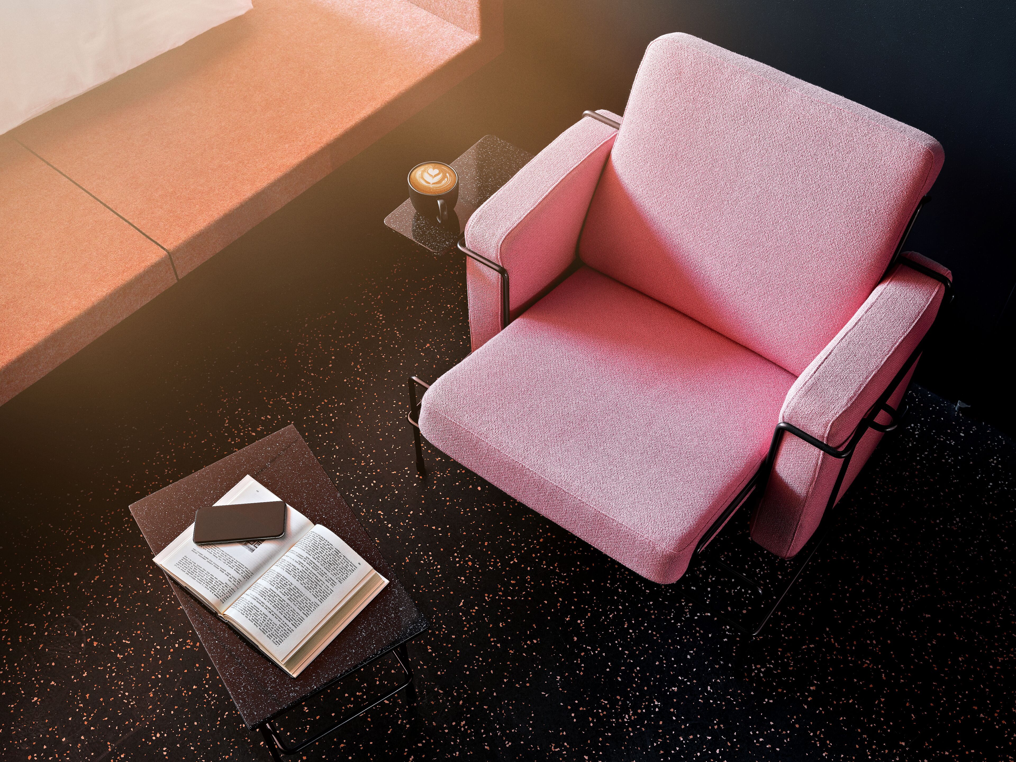 A pink armchair with a book and a smartphone on a table.