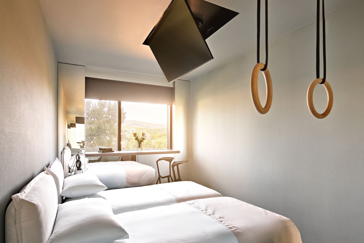 Una habitación de hotel moderna con cama, escritorio y ventana con vistas a la ciudad.