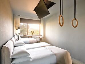 Une chambre d’hôtel moderne, équipée d’un lit, d’un bureau et d’une fenêtre donnant sur la ville.