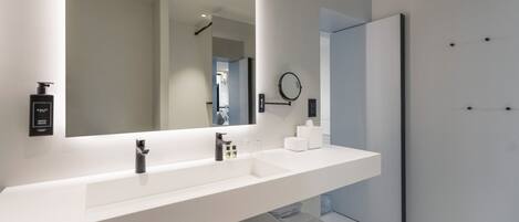 A modern bathroom with a large mirror, a white sink, and a towel rack.