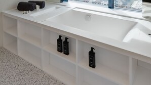 Un baño moderno con un ventanal grande, un lavabo blanco y un espejo.