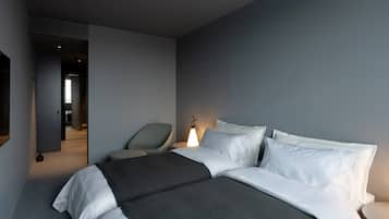 A hotel room with a large bed, a chair, a bedside table, and a lamp.