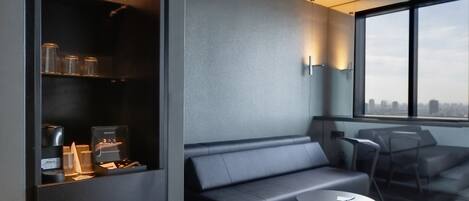 A modern living room with a sofa, a coffee table, and a built-in shelving unit with kitchen appliances.