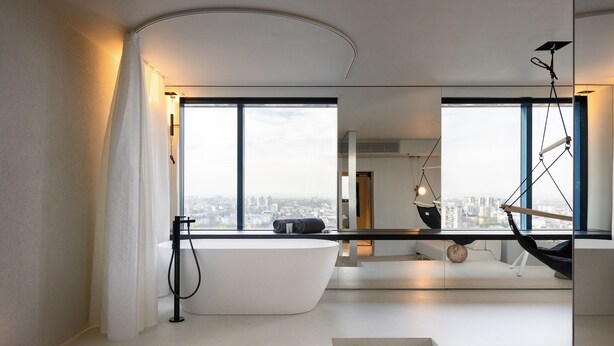 Un baño moderno con una bañera independiente, un ventanal con vistas a la ciudad y un diseño minimalista.