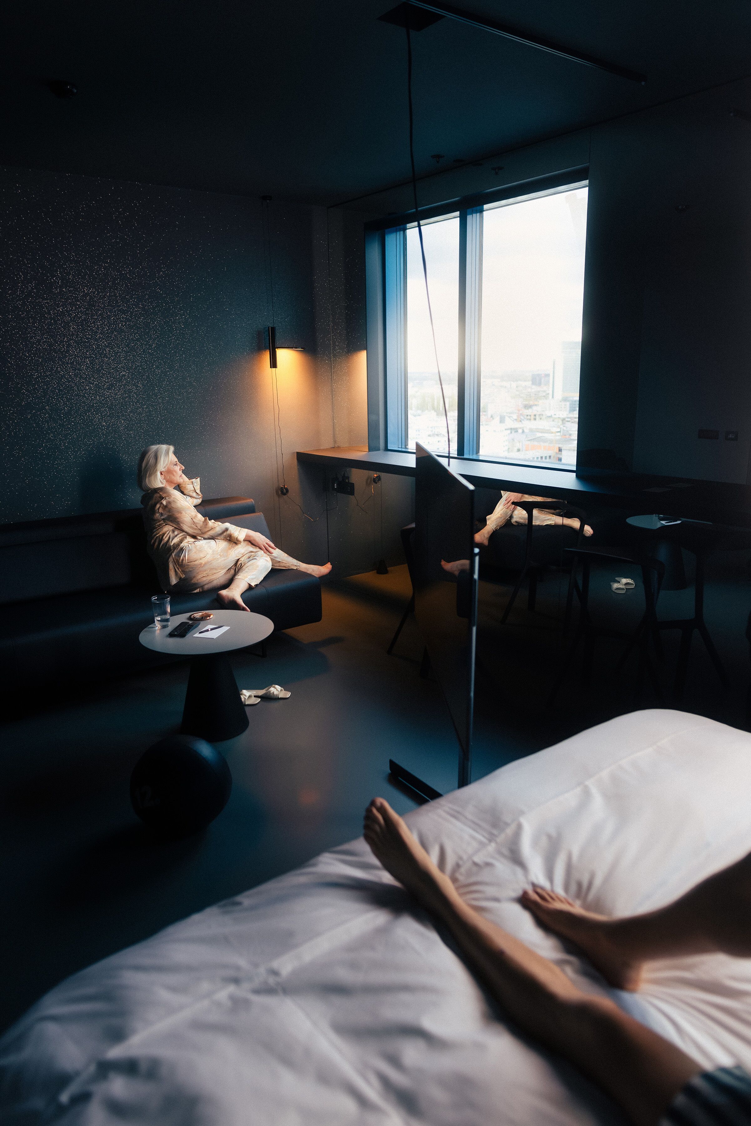 Una habitación tenuemente iluminada con una cama, una silla y un escritorio.