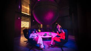 A conference room with a large spherical light fixture, round tables, and modern chairs.